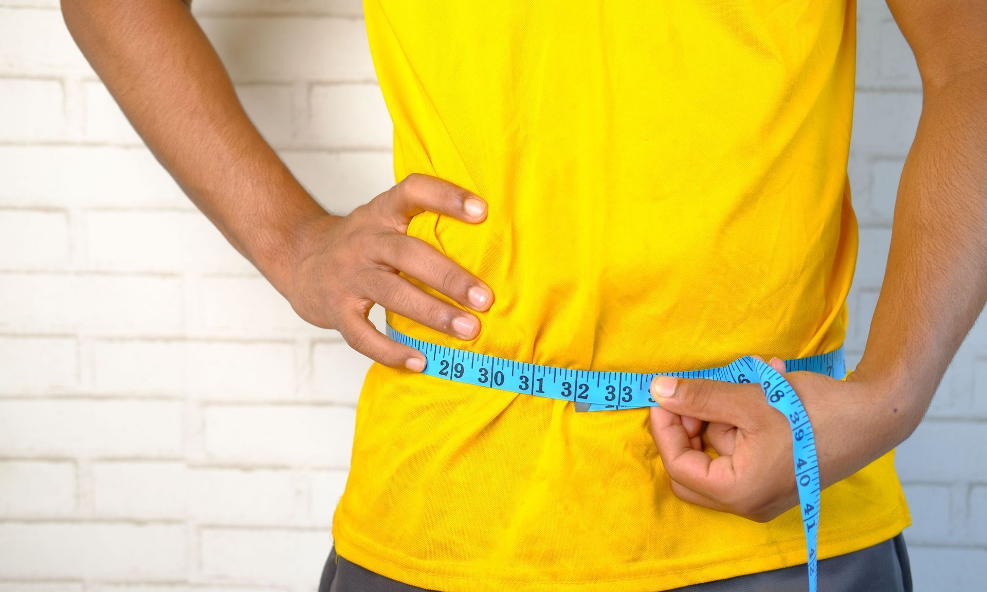 Learn More About Nutritional Therapy A man is measuring his waist with a tape measure.