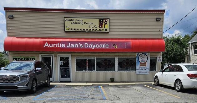 Daycare building with red awning. Sign reads "Auntie Jan's Daycare". Cars parked out front.