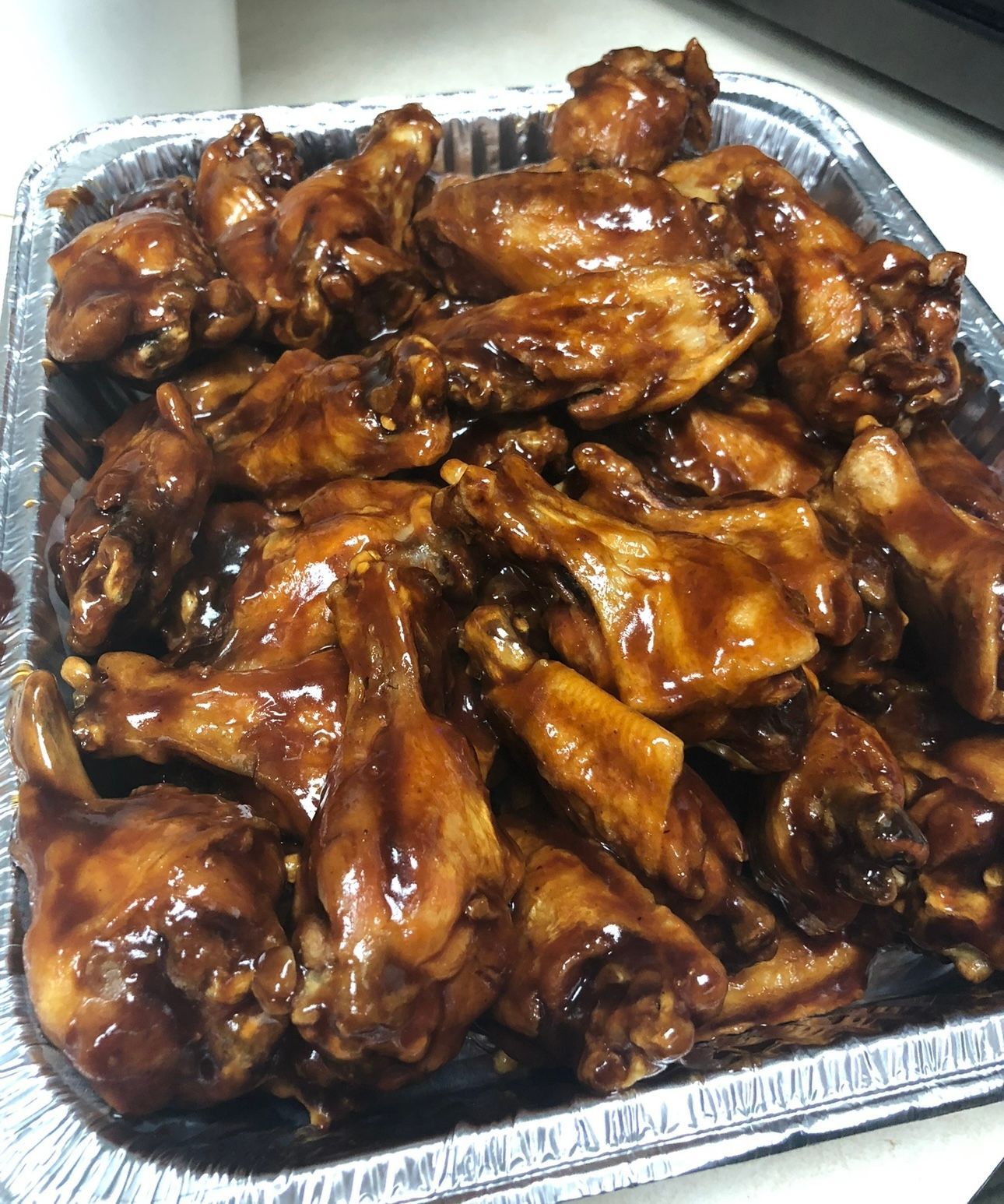 A tray of chicken wings covered in barbecue sauce