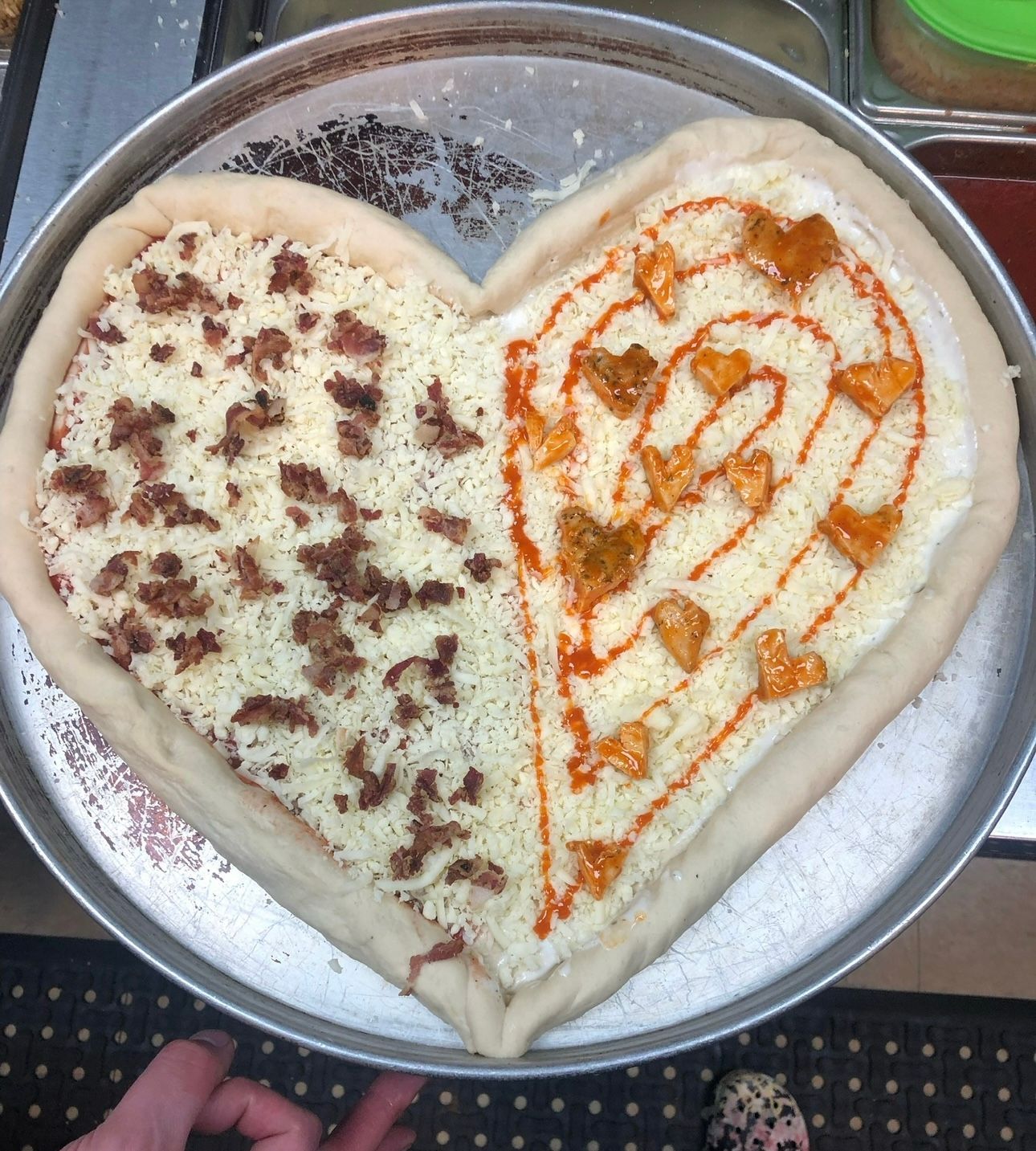 A heart shaped pizza with two different toppings on it