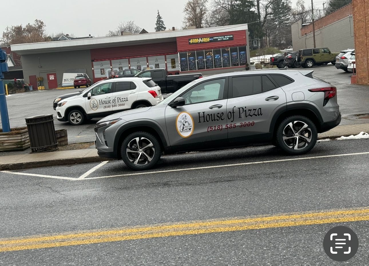 A car is parked on the side of the road in front of a building.