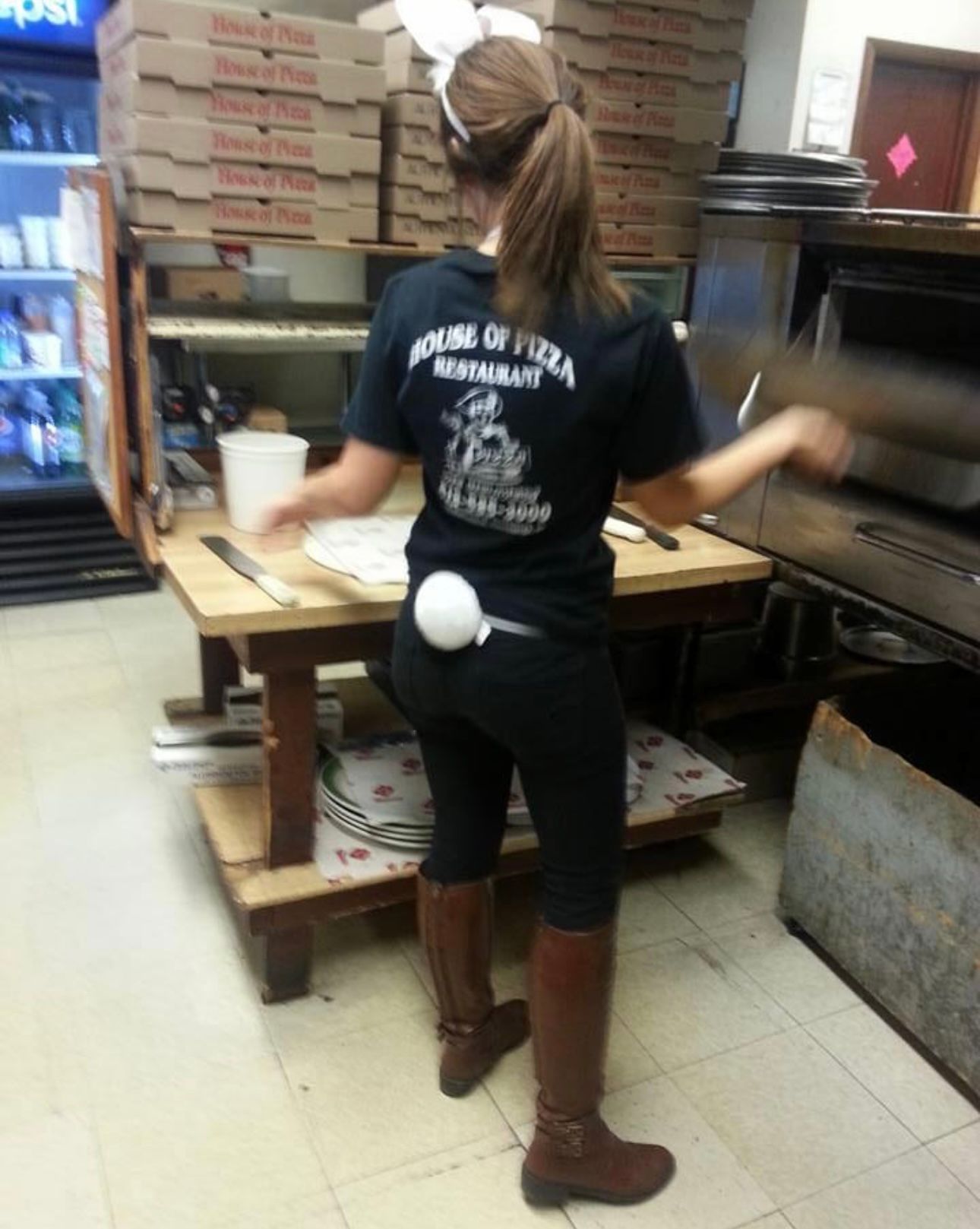 A woman wearing a shirt that says home of pizza restaurant