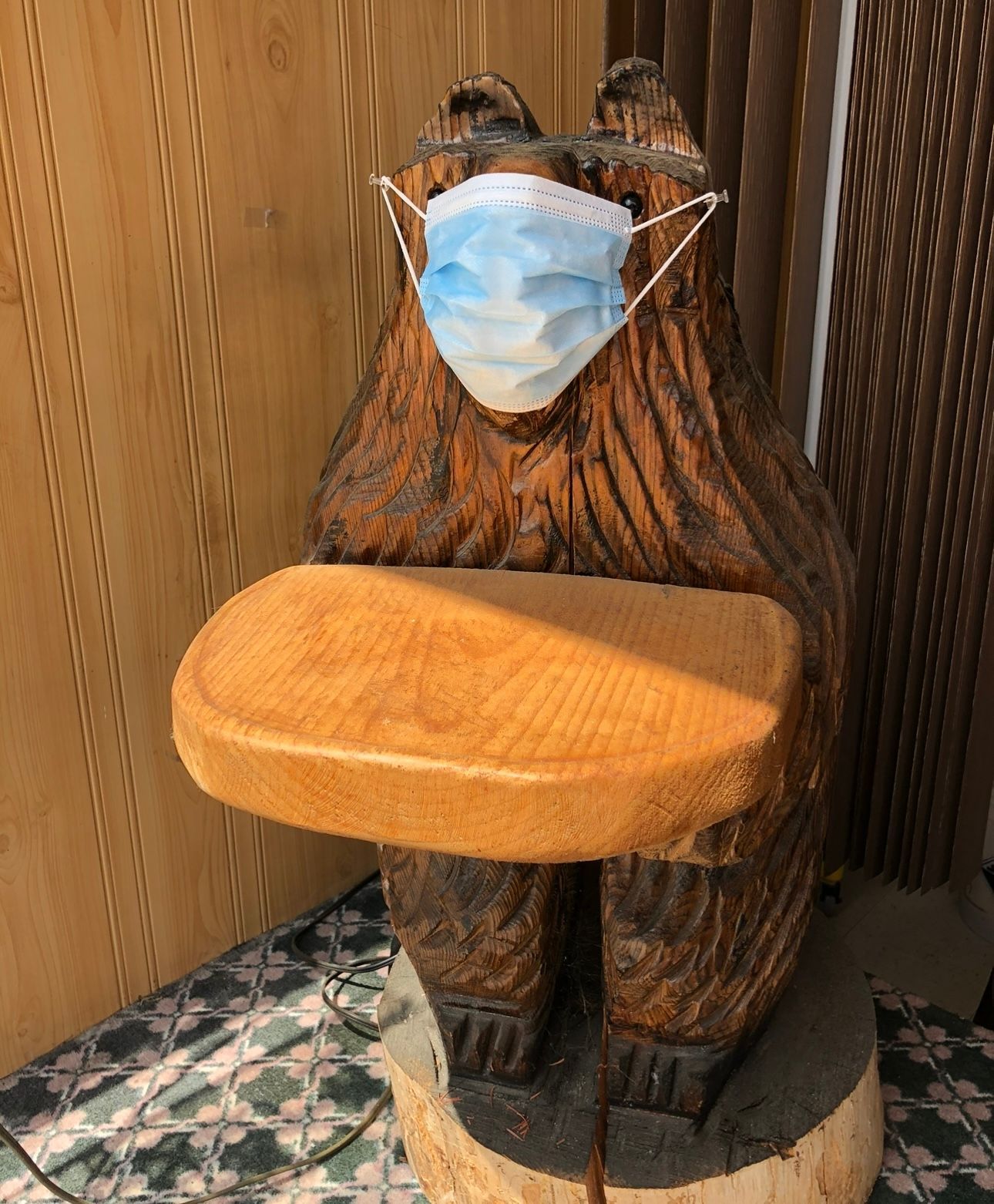 A wood carving of a bear wearing a face mask