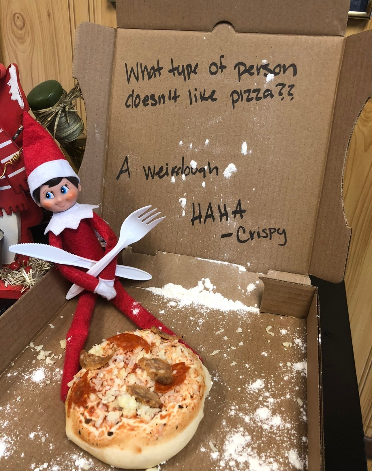An elf on the shelf is sitting in a pizza box