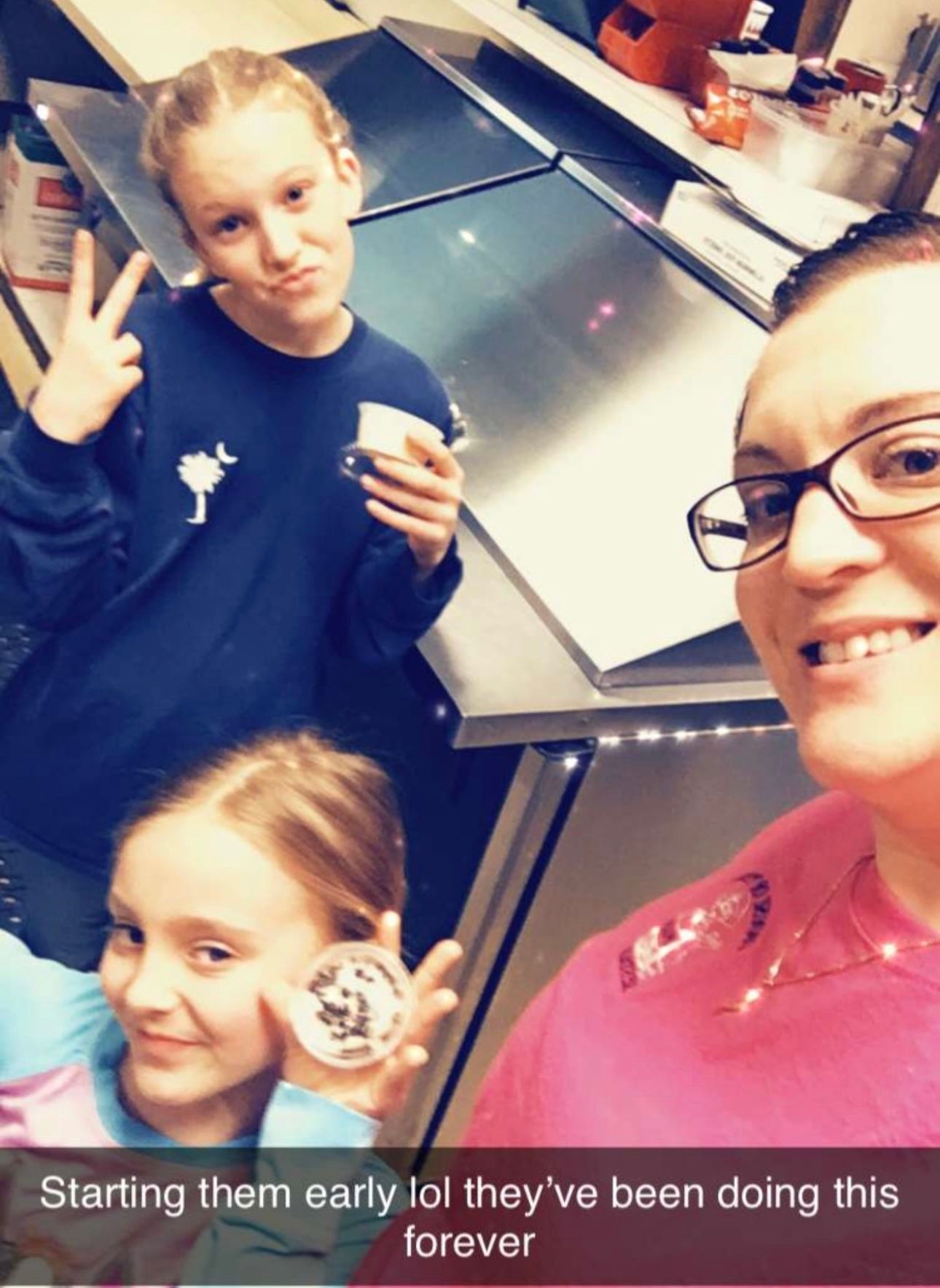 A woman and two girls are posing for a picture with the caption starting them early lol they 've been doing this forever