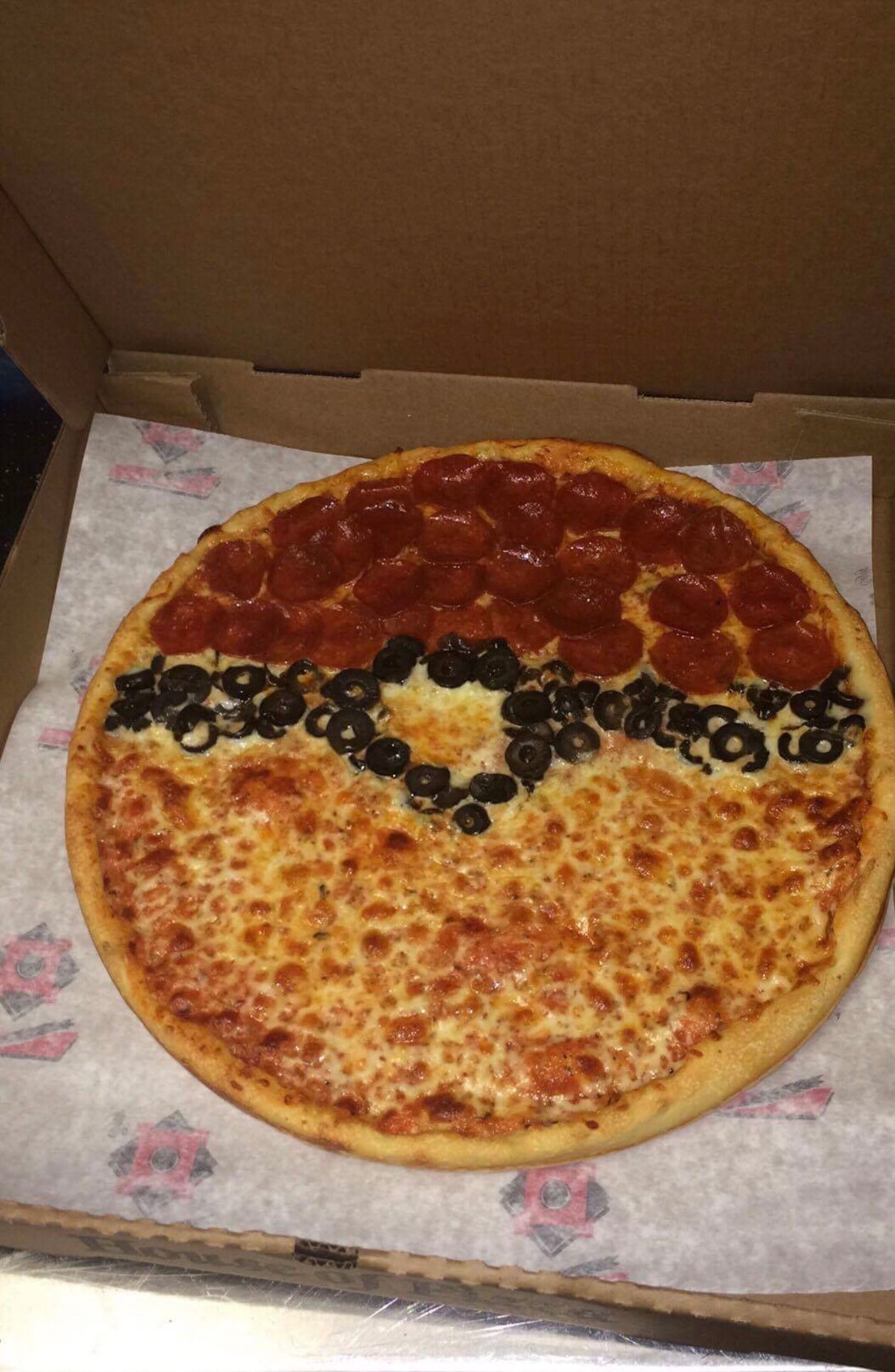 A pizza with pepperoni , cheese and olives on it is in a box.