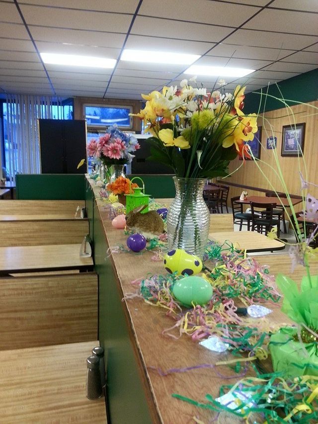 A restaurant with flowers and easter eggs on the counter
