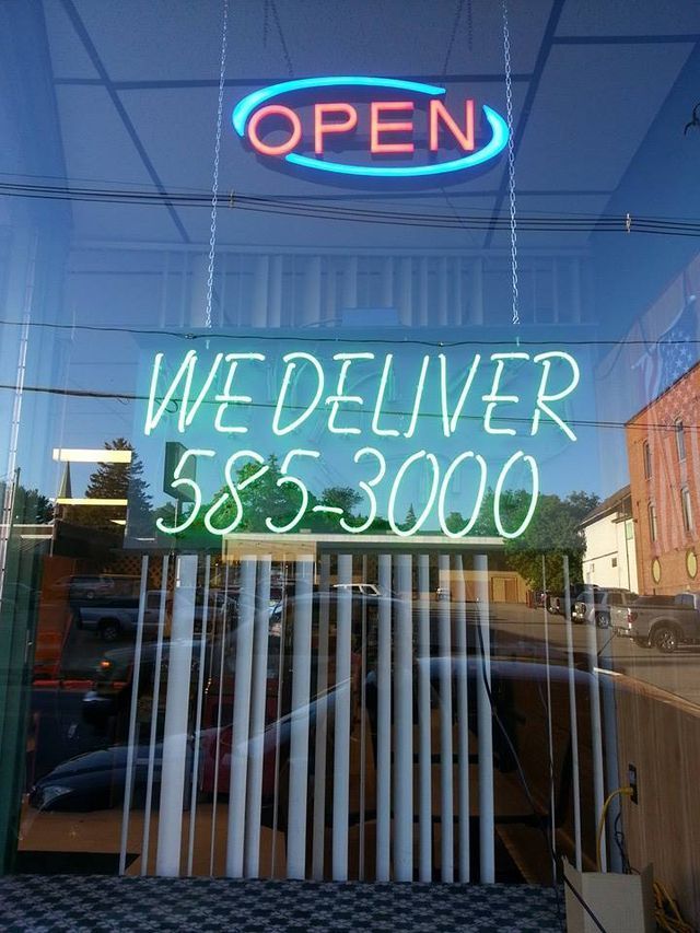 A neon sign that says open and we deliver written on it