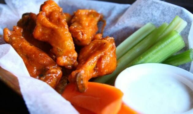 A basket of chicken wings , carrots , celery and ranch dressing.