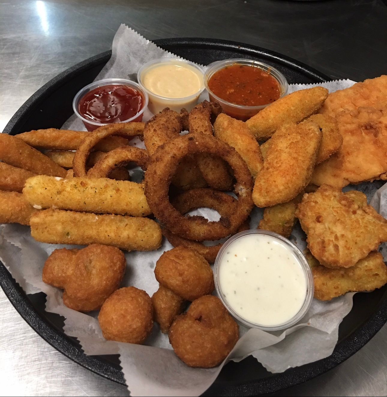 A tray of fried food including onion rings mozzarella sticks and chicken nuggets