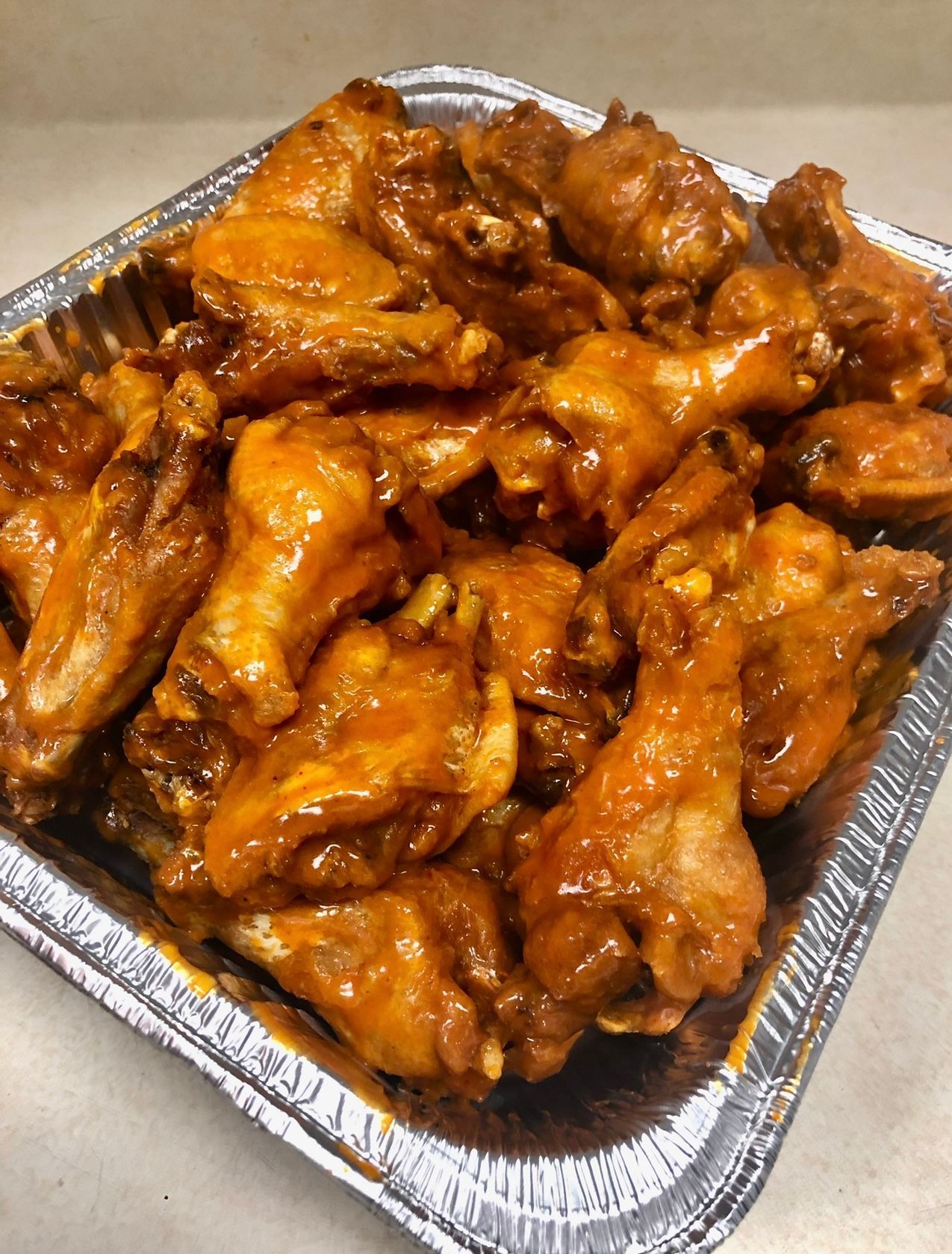 A tray of chicken wings in a buffalo sauce on a table.