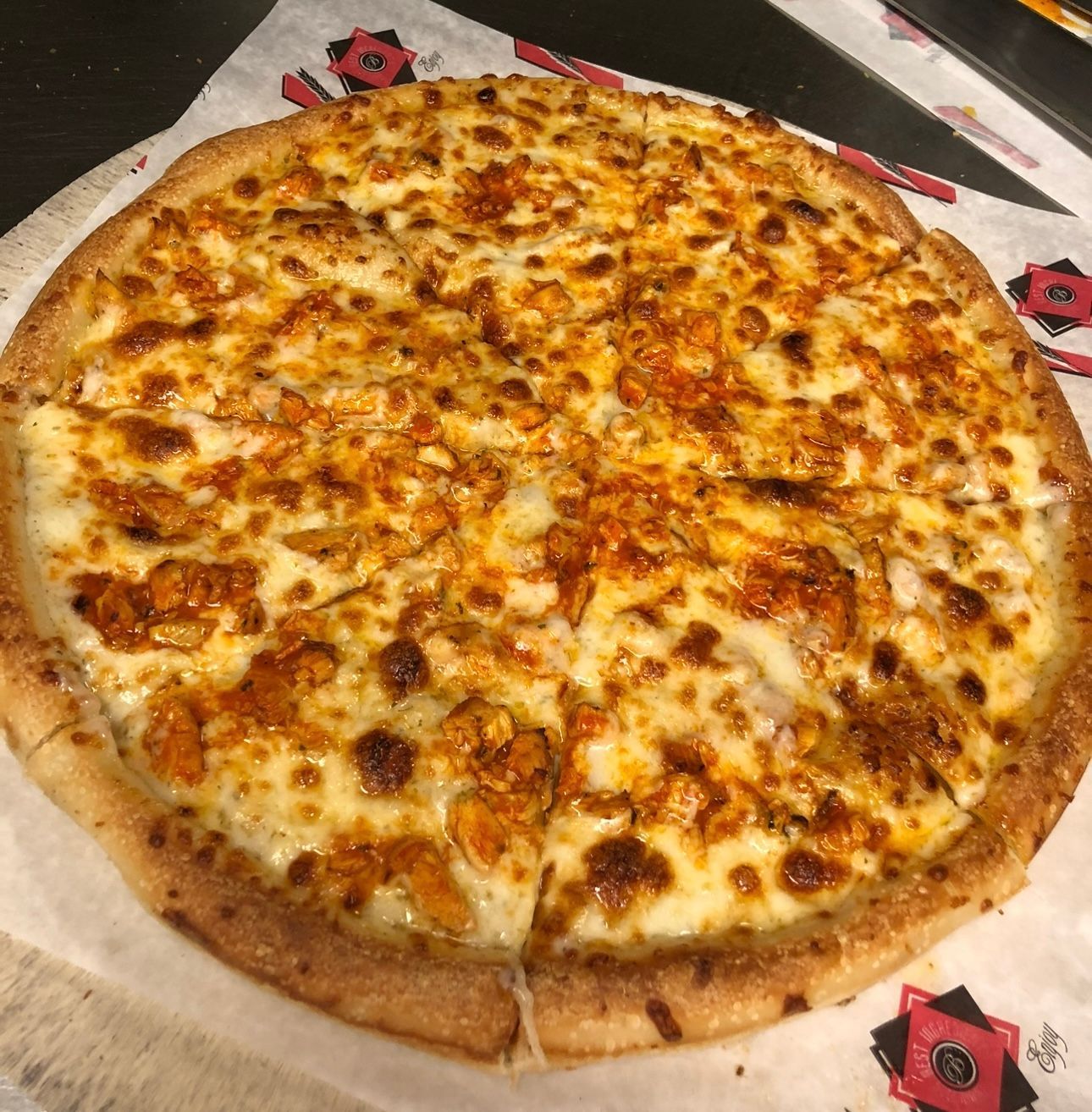 A pizza is sitting on top of a piece of paper on a table.