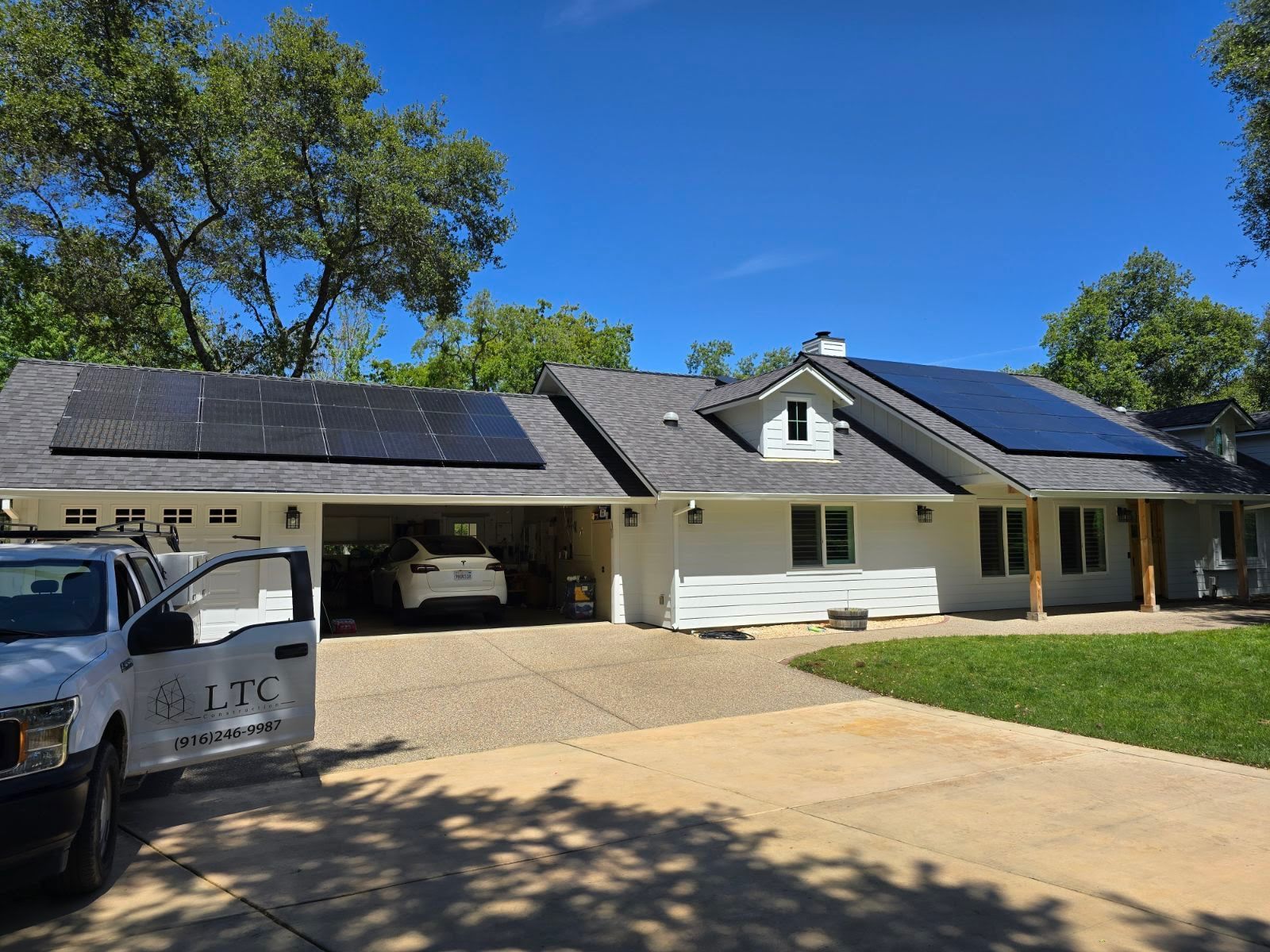 A white house with solar panels on the roof and a white truck parked in front of it