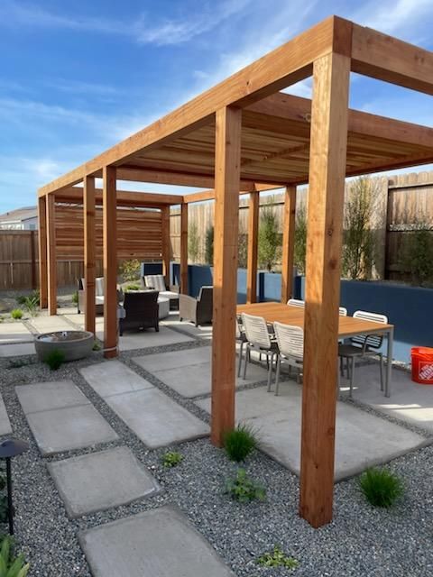 A wooden pergola with a table and chairs underneath it