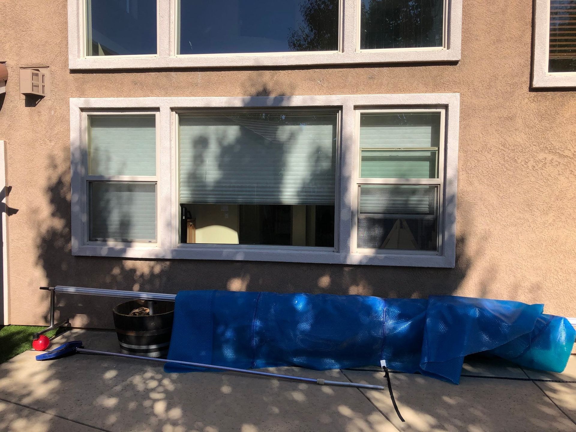 A large window on the side of a house with a blue tarp covering it.