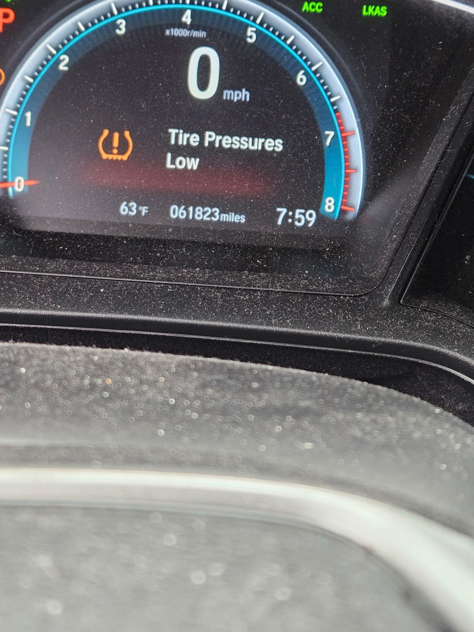 Car dashboard display warning: tire pressure low, with speed at 0 mph.