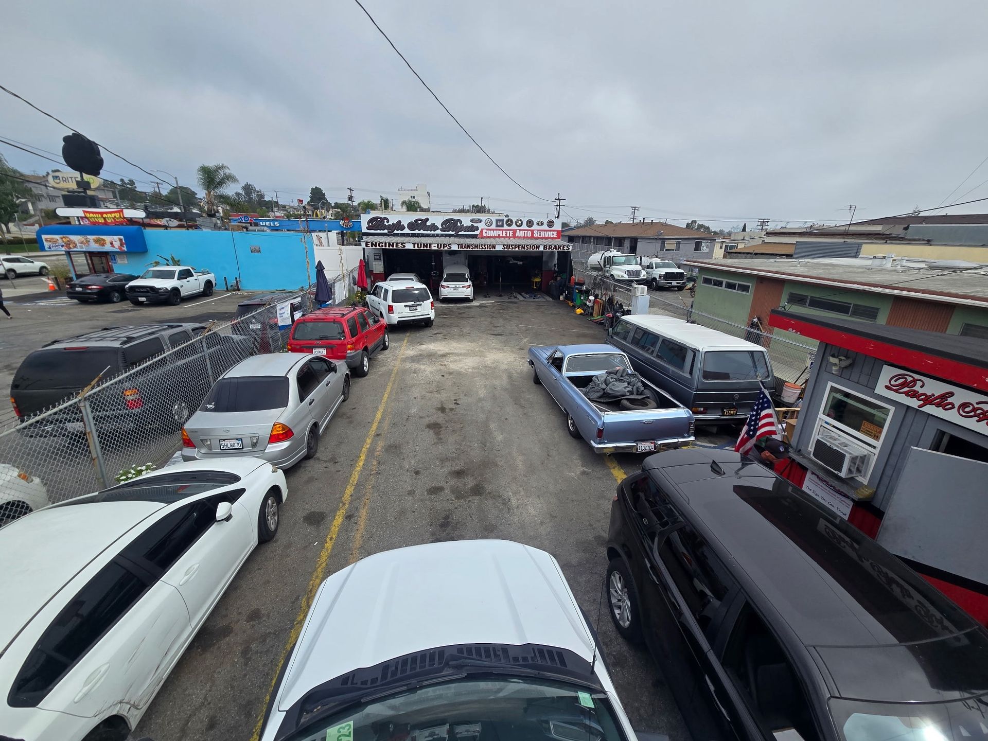 Parking lot crowded with cars outside a low commercial building under a cloudy sky