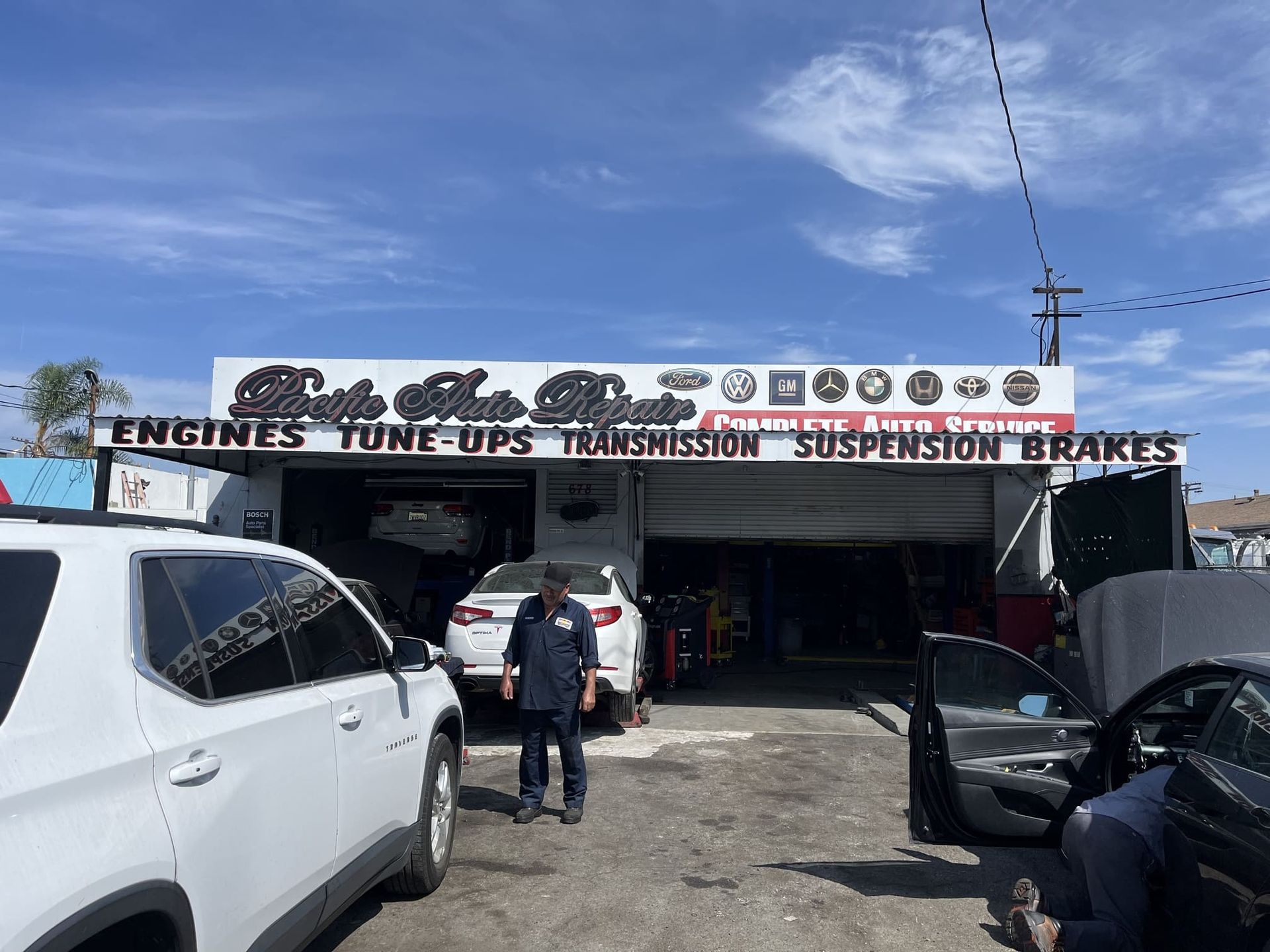 Auto repair shop storefront with cars parked outside under a bright blue sky