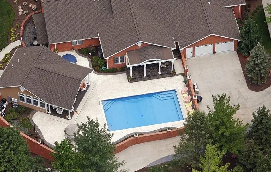 Aerial view of a house with a pool, gazebo, and garage. The pool is blue, and the buildings have brown roofs.