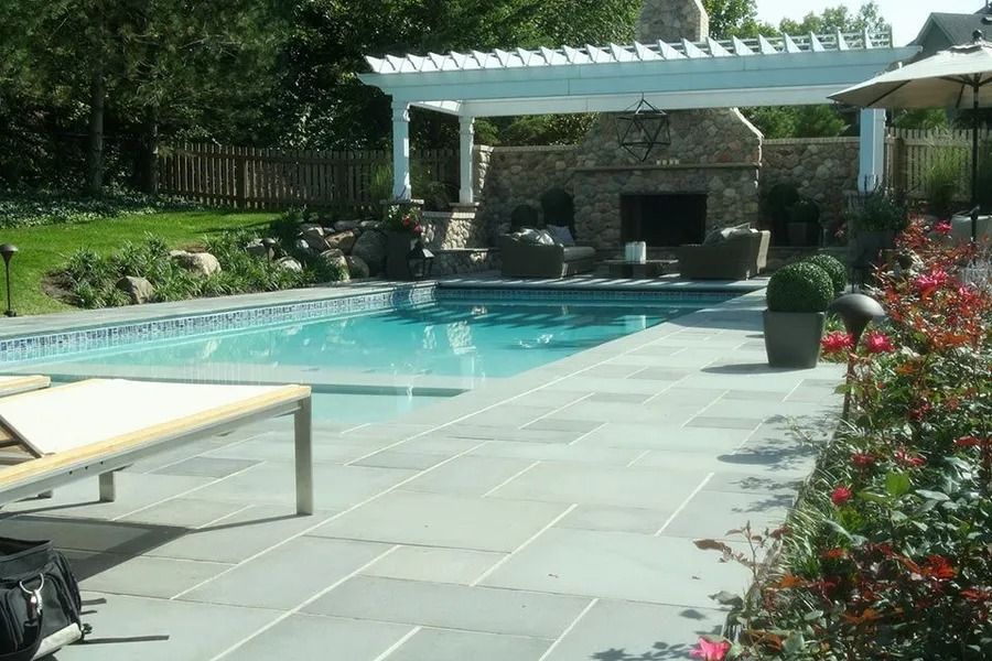 Swimming pool with stone patio, outdoor fireplace, and pergola.