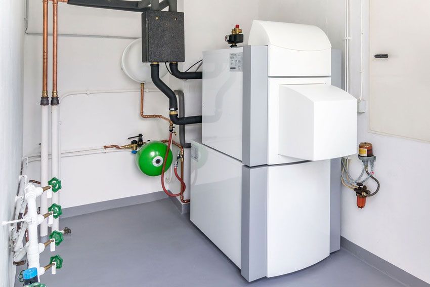 A room with a boiler and pipes in it.