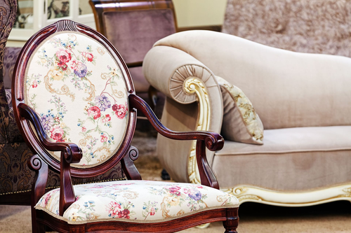 Floral upholstered antique chair beside a cream sofa in a vintage living room