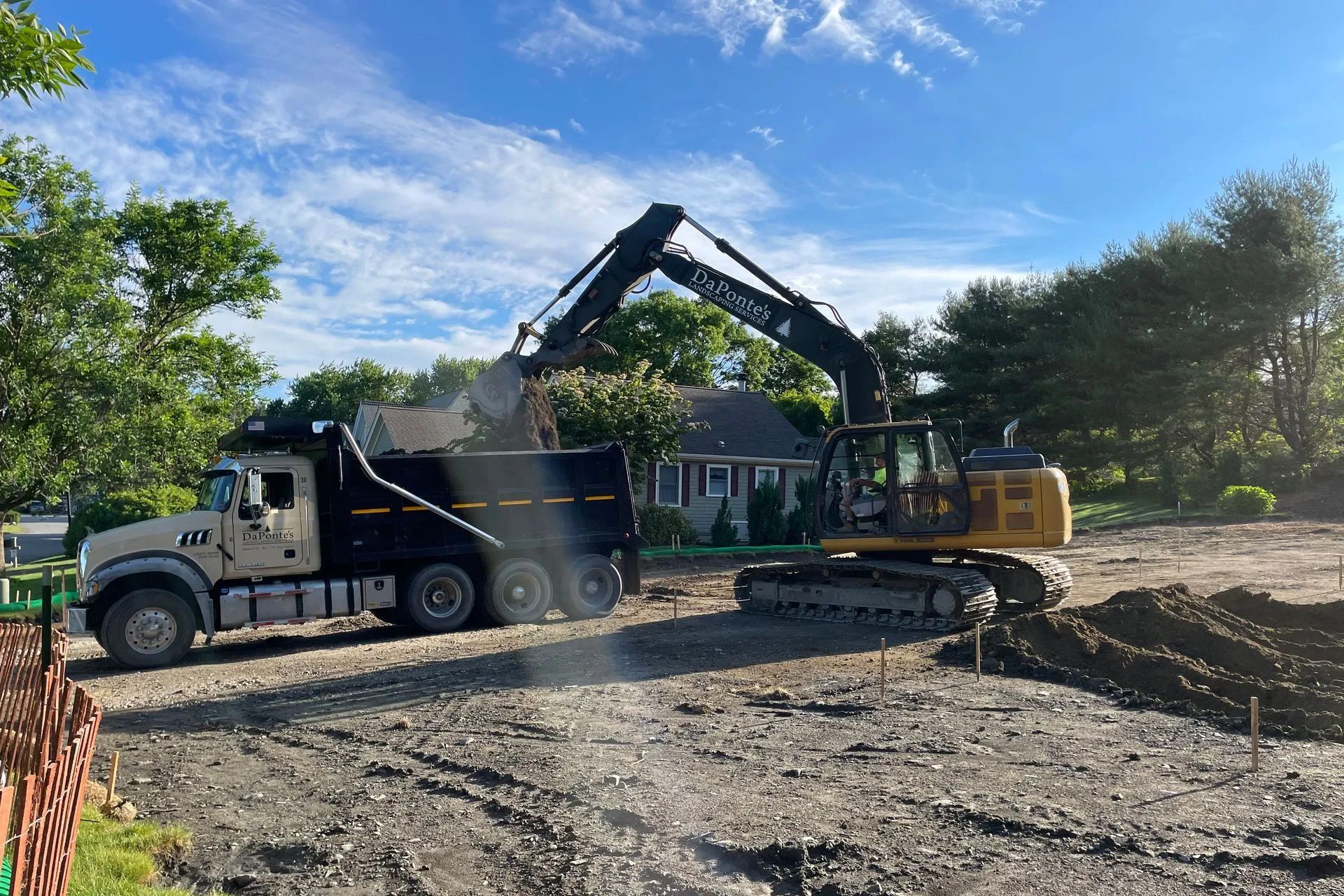 A dump truck is being loaded with dirt by an excavator.