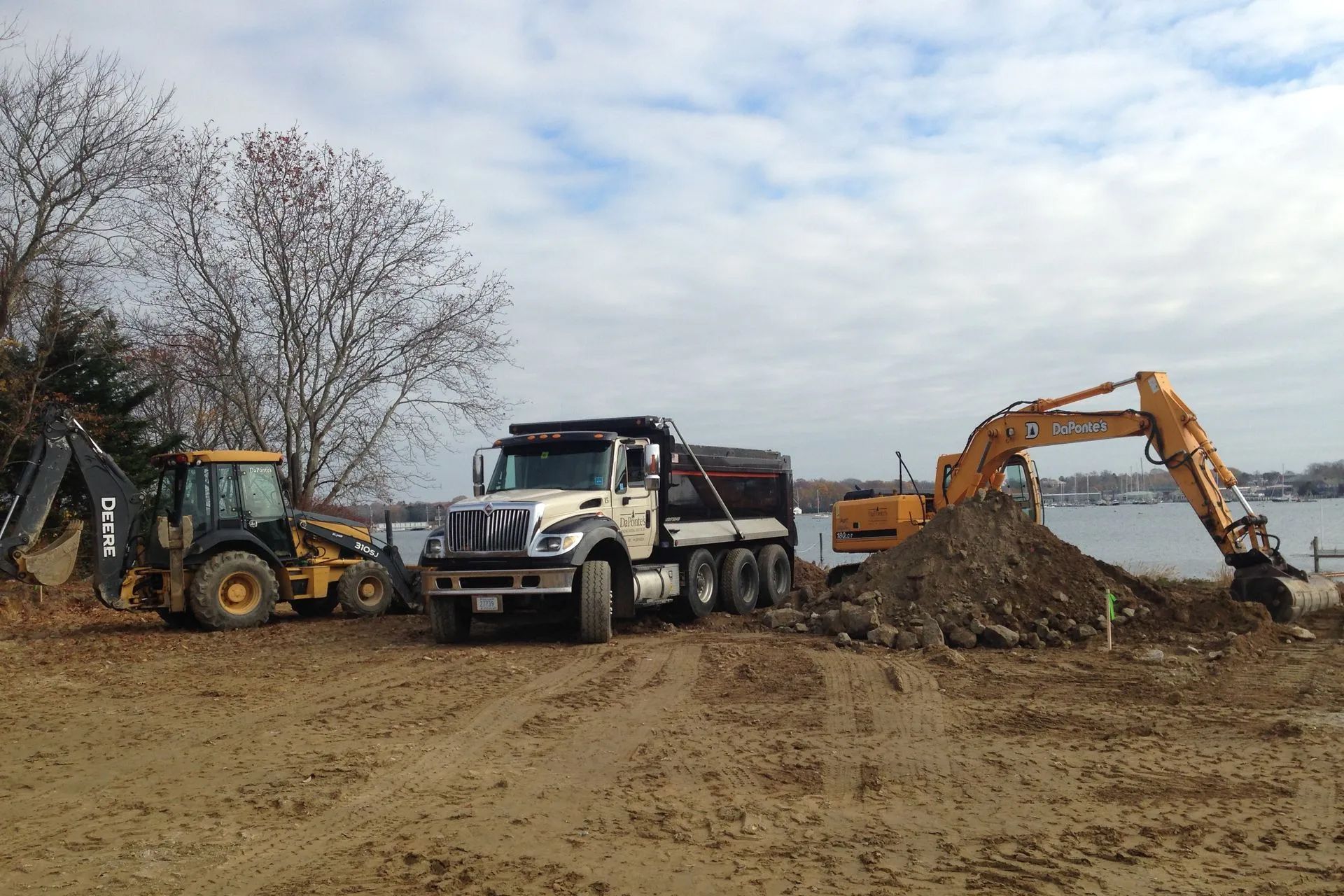 A dump truck is parked next to a large pile of dirt.