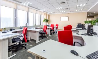 Bright modern office with red chairs, desks, computers, and large windows