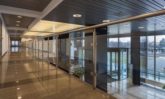 Empty modern glass hallway with polished floor and ceiling lights
