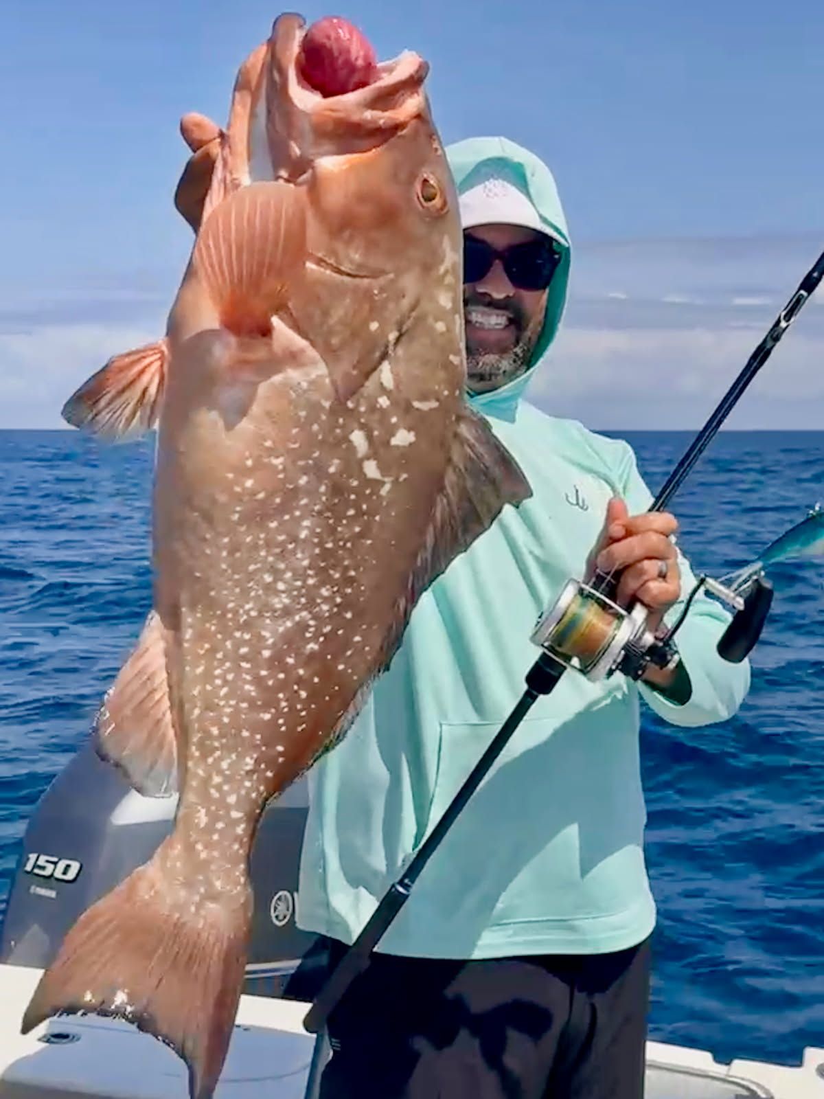 A man is holding a large fish on a boat.