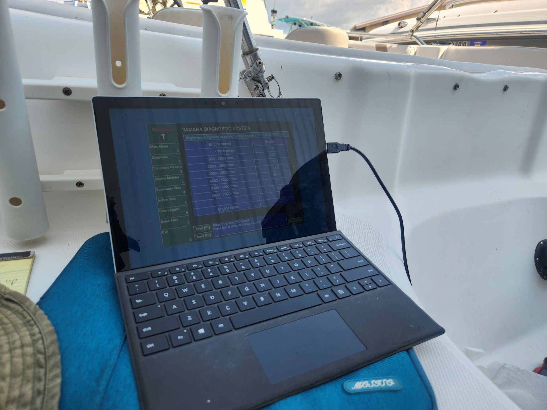 A laptop is plugged into a charger on a boat.