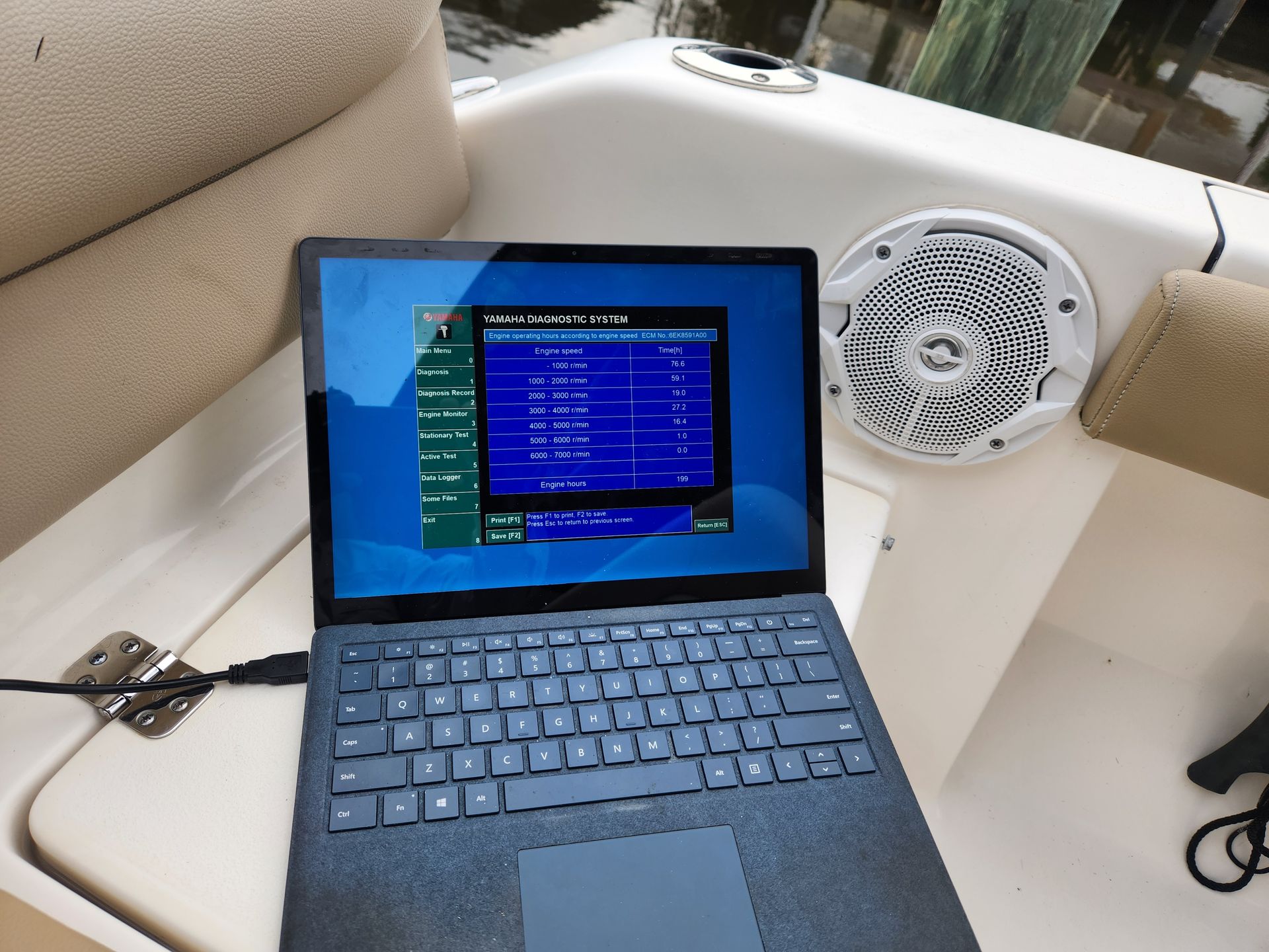 A laptop is plugged into a speaker on a boat