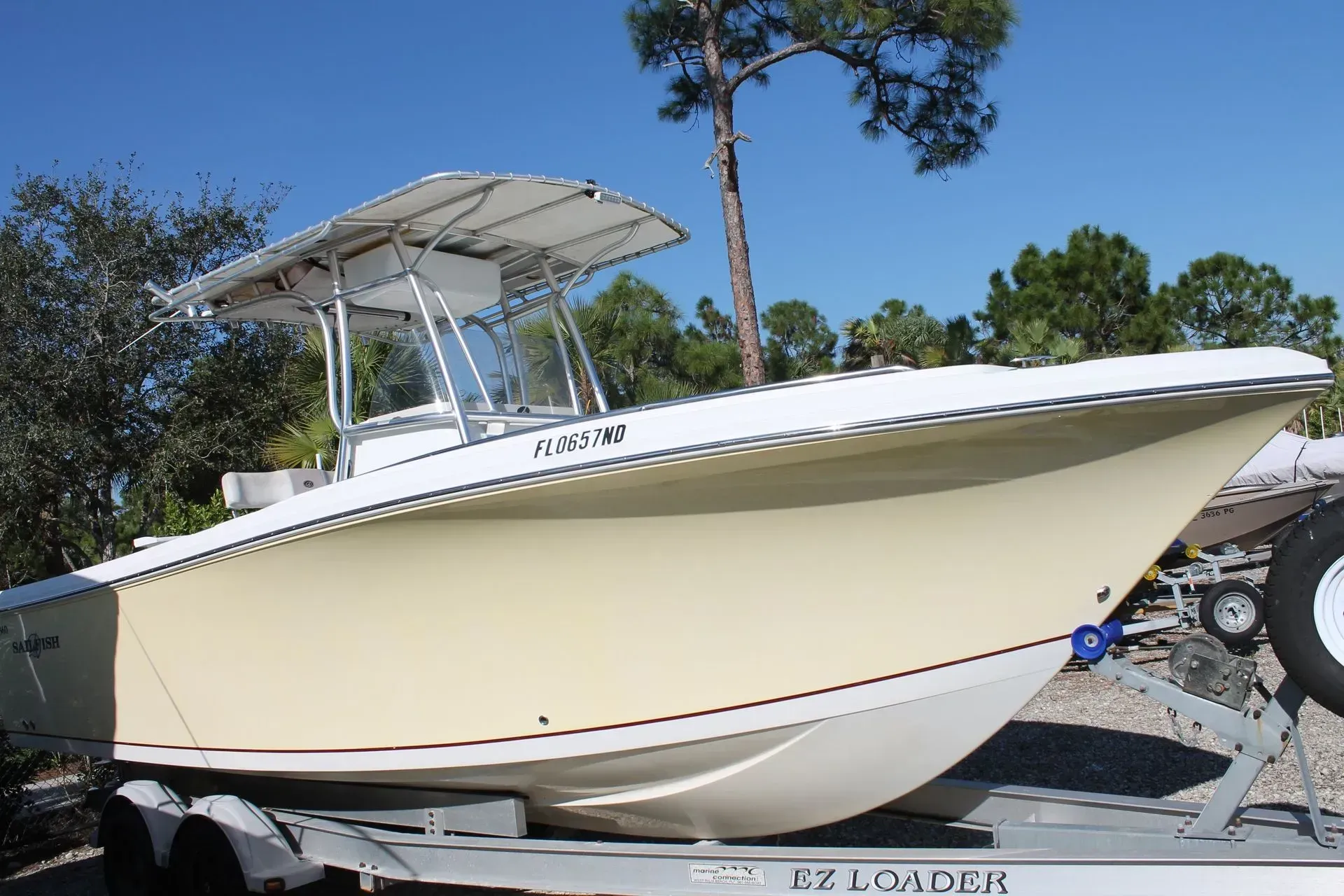 A white boat with a roof is on a trailer.