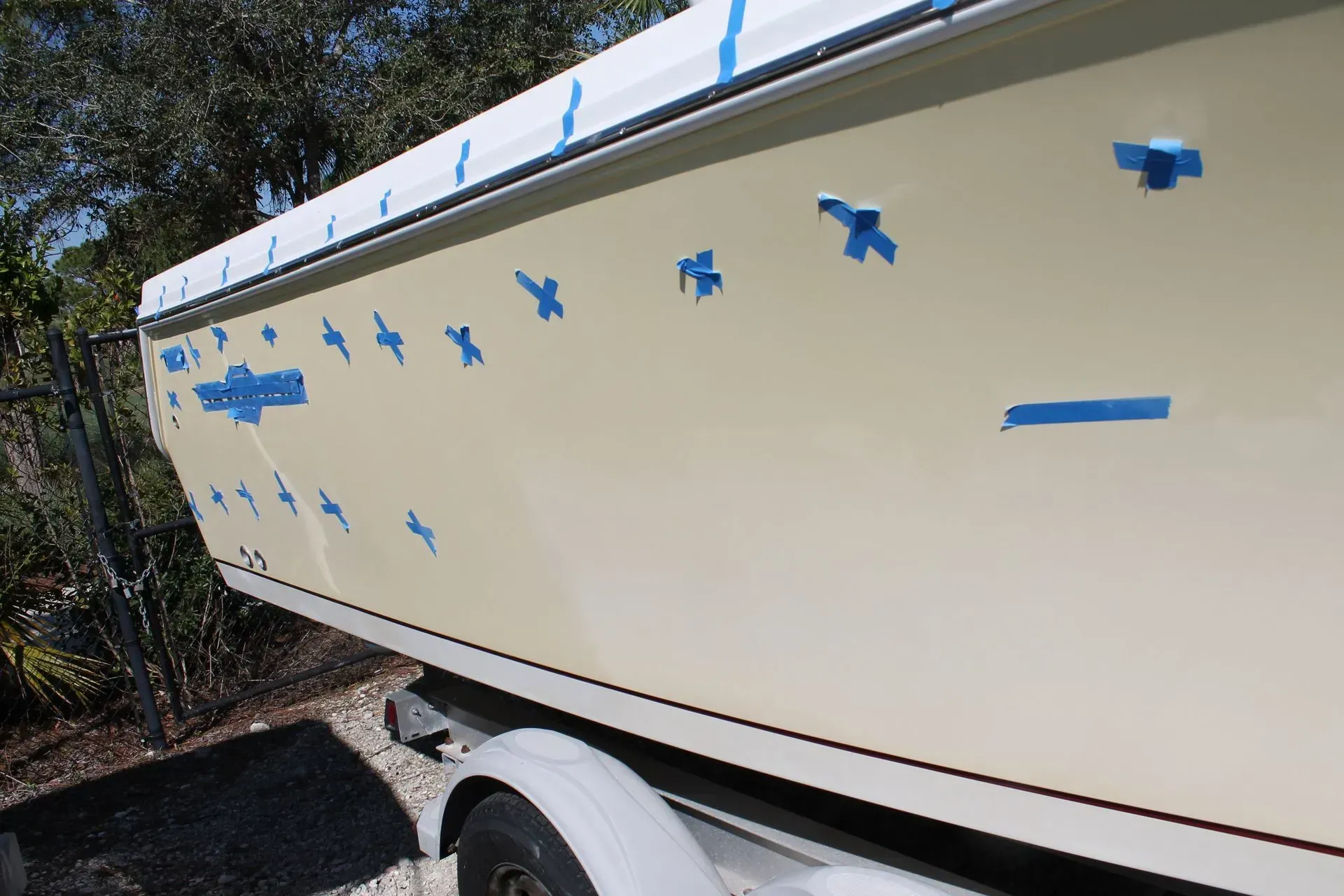 A boat with blue tape on it is sitting on a trailer.
