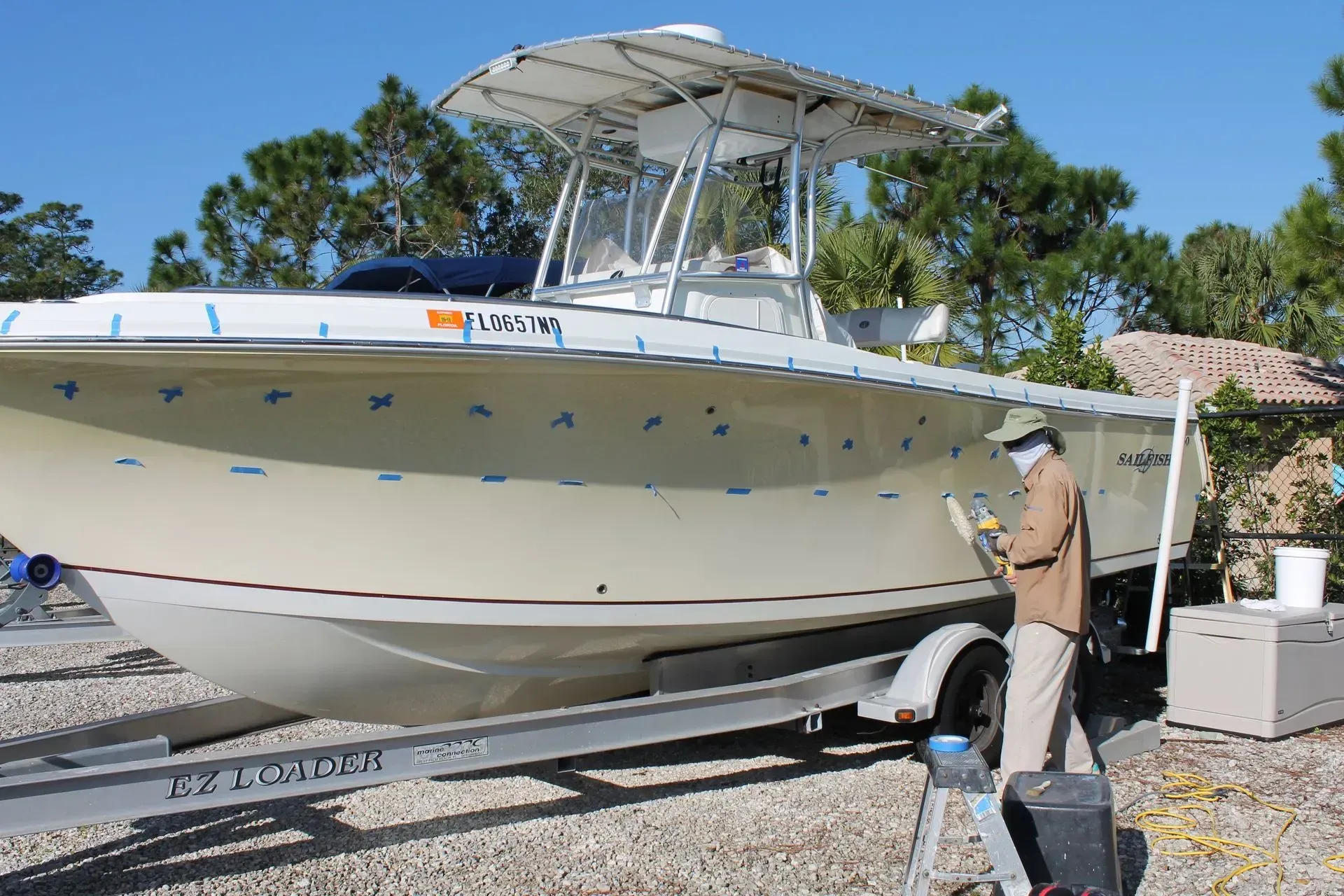 A man is painting a boat with a license plate.