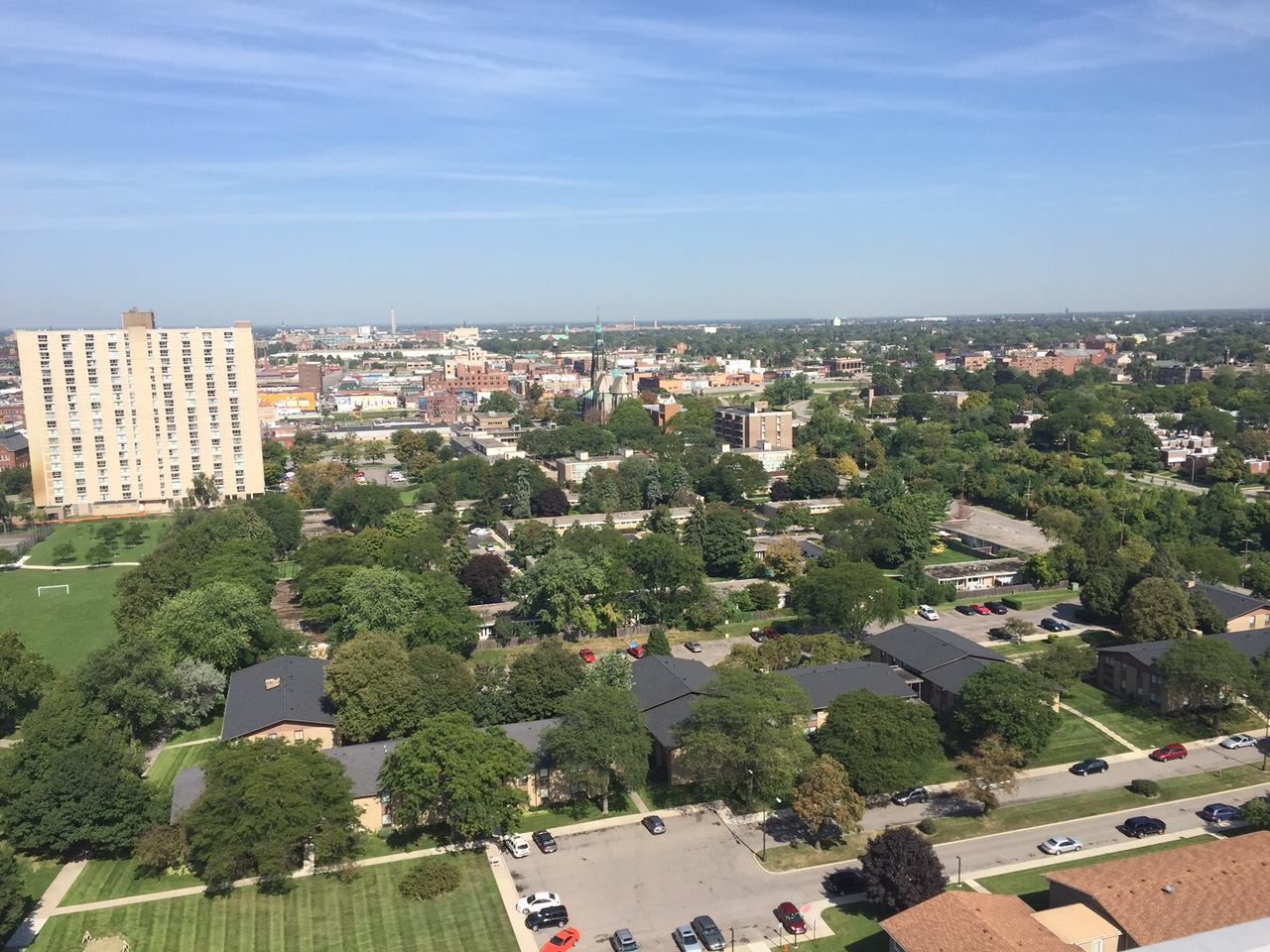 Aerial view of a leafy residential neighborhood with low-rise buildings under a clear blue sky