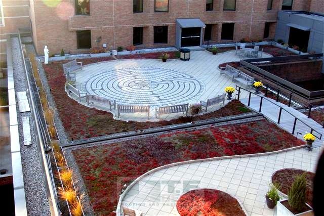 Rooftop courtyard with circular labyrinth paths, brick buildings, and autumn-colored landscaping