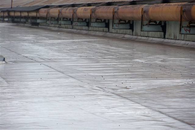 Wet, empty rooftop walkway beside rusted ventilation ducts