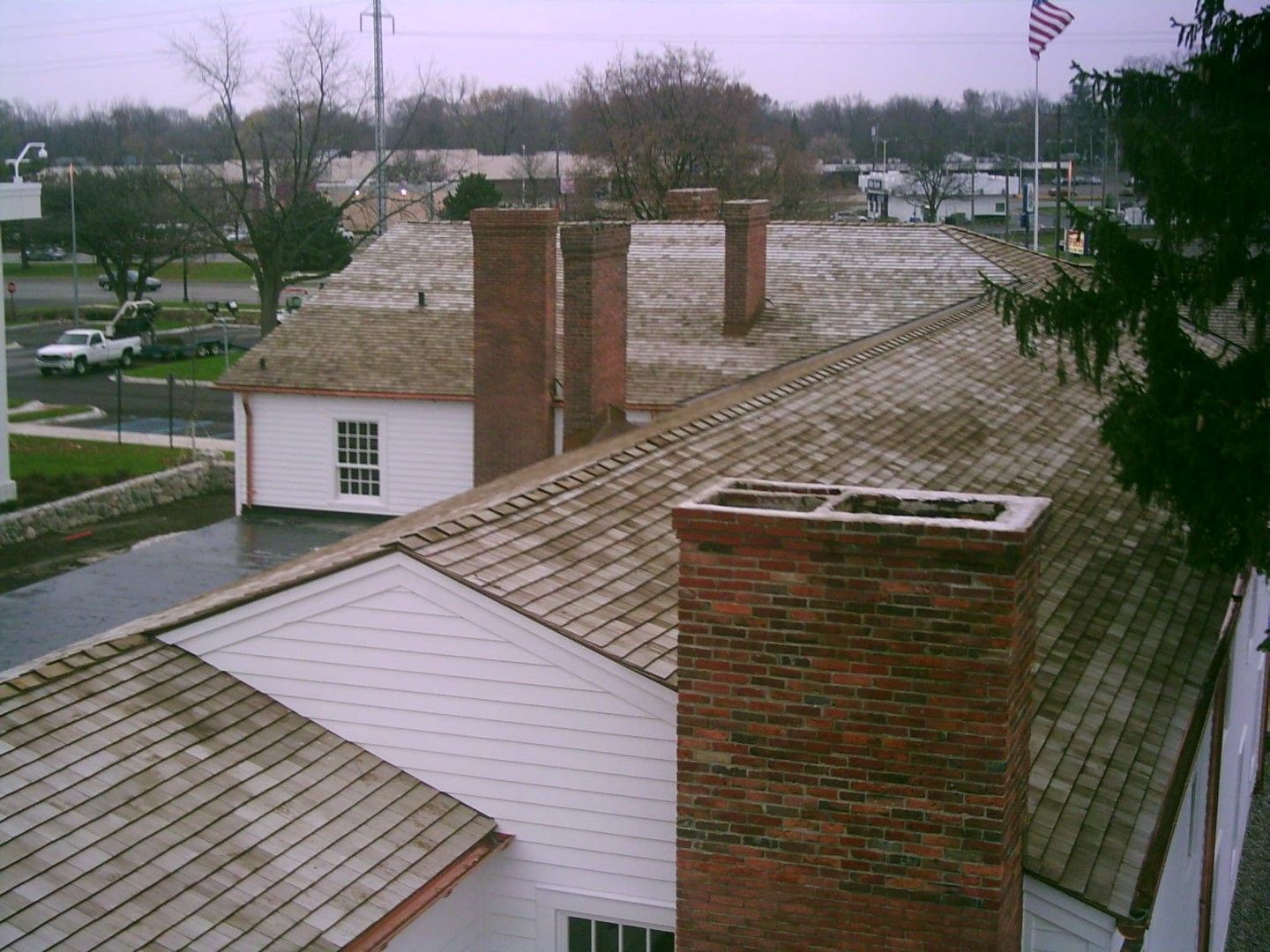 Snow-dusted rooftop with brick chimneys and a flag in the distance on an overcast day
