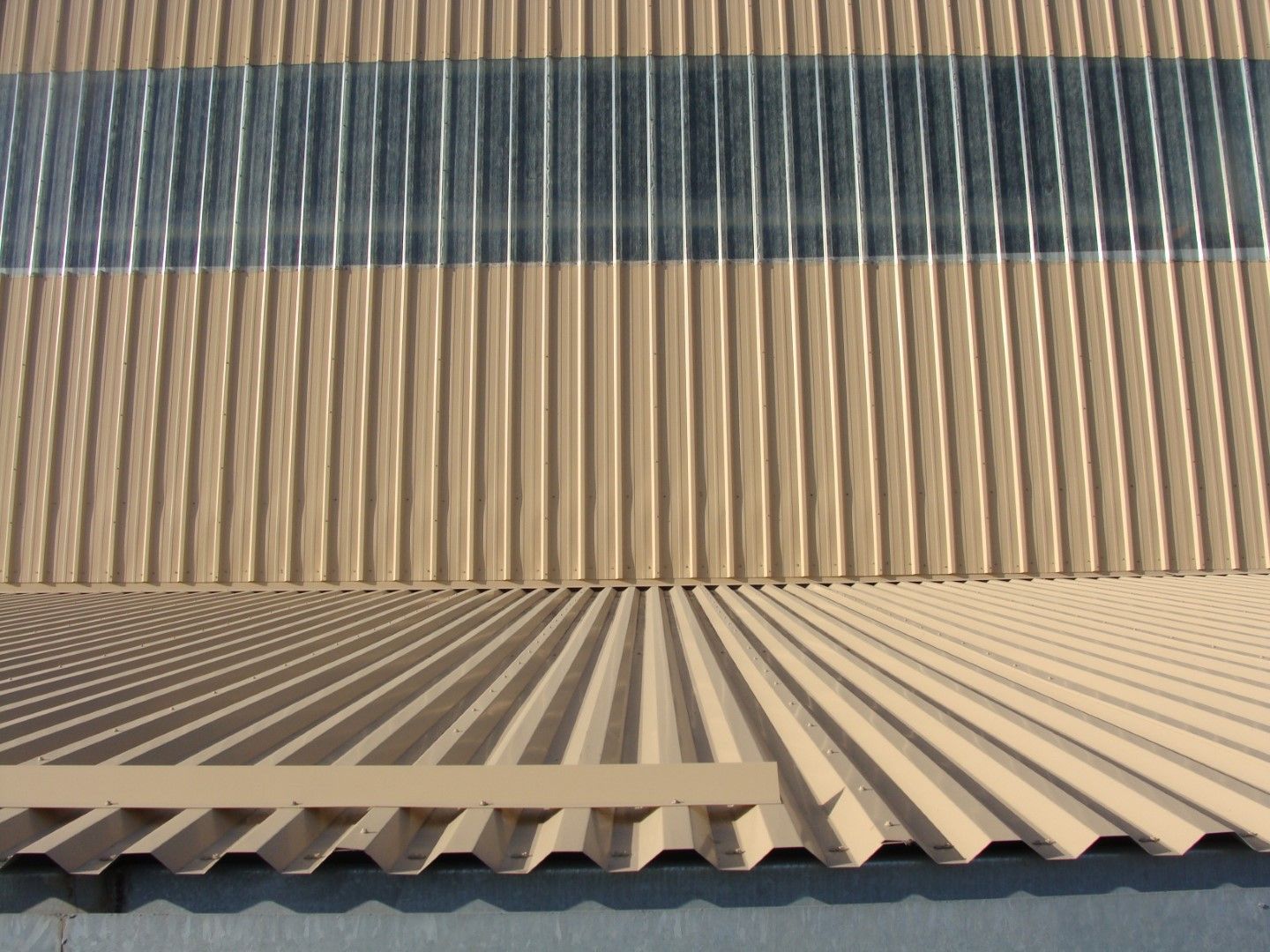 Rows of corrugated metal roofing in gray, tan, and beige forming a geometric pattern