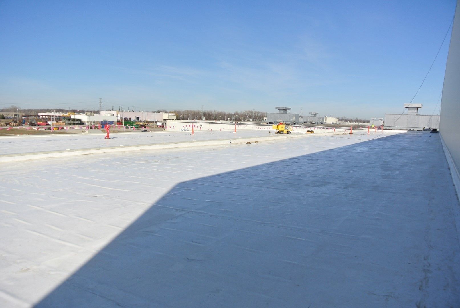 Snow-covered rooftop with a large shadow under a clear blue sky