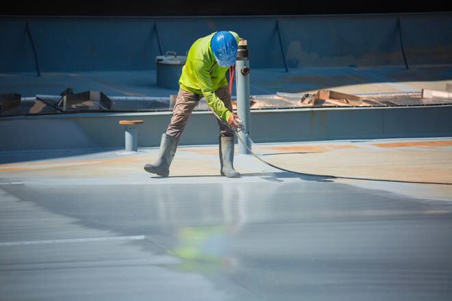 Worker in a neon jacket smoothing wet concrete with a long-handled tool on a construction site