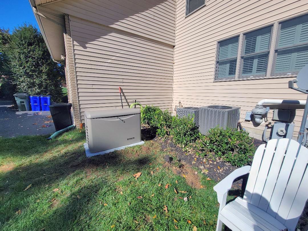 A lawn chair is sitting in front of a house next to a generator.