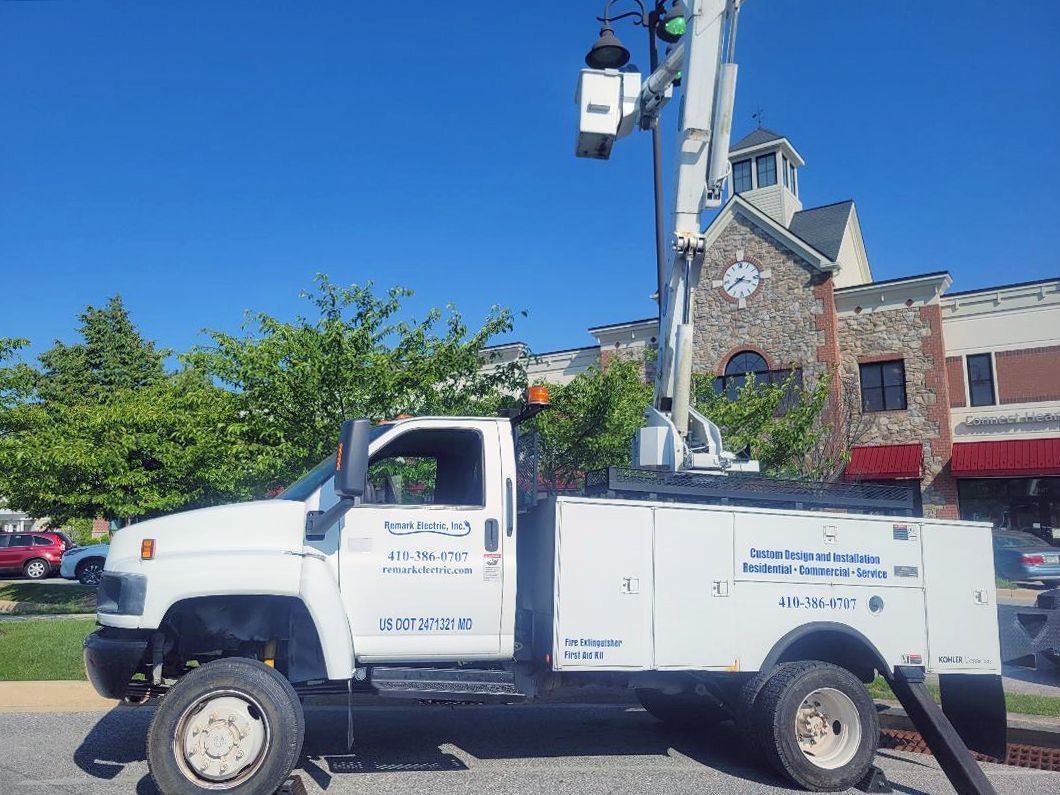 A white truck with a bucket on the back is parked in front of a building
