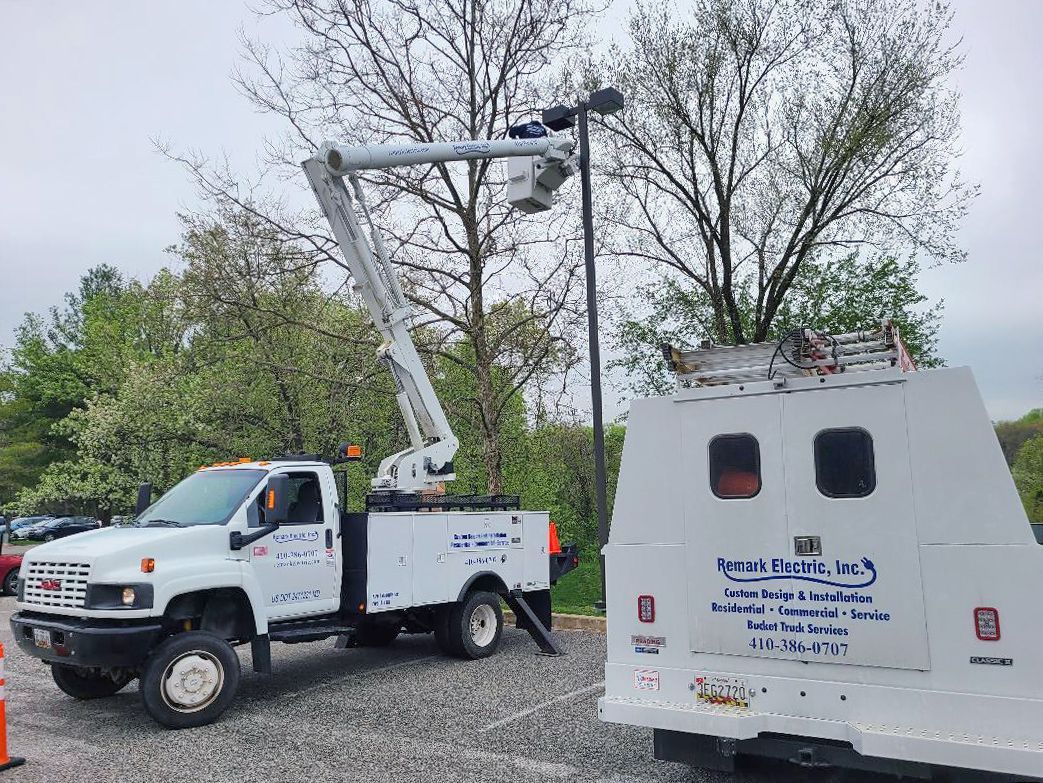 A white truck with a crane on top of it is parked next to a white van.