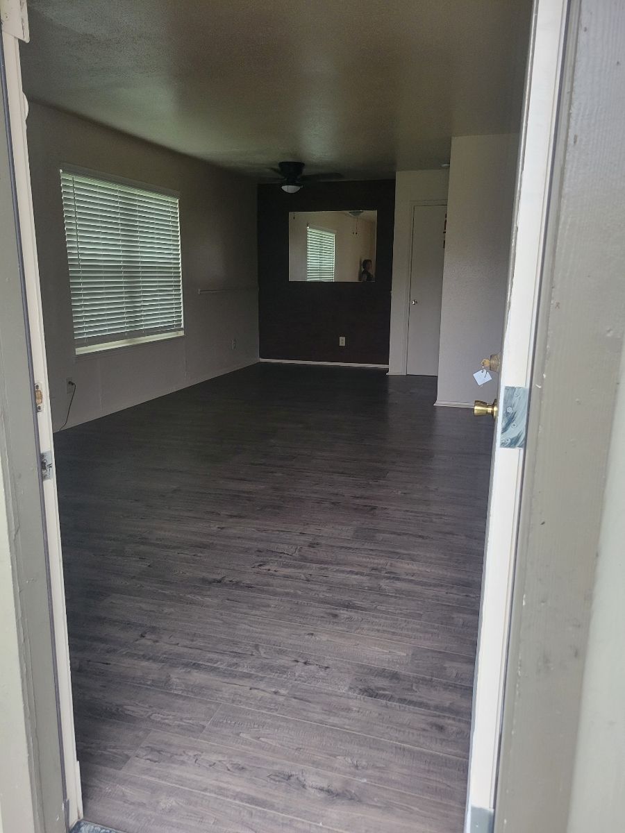 An empty living room with hardwood floors and a window