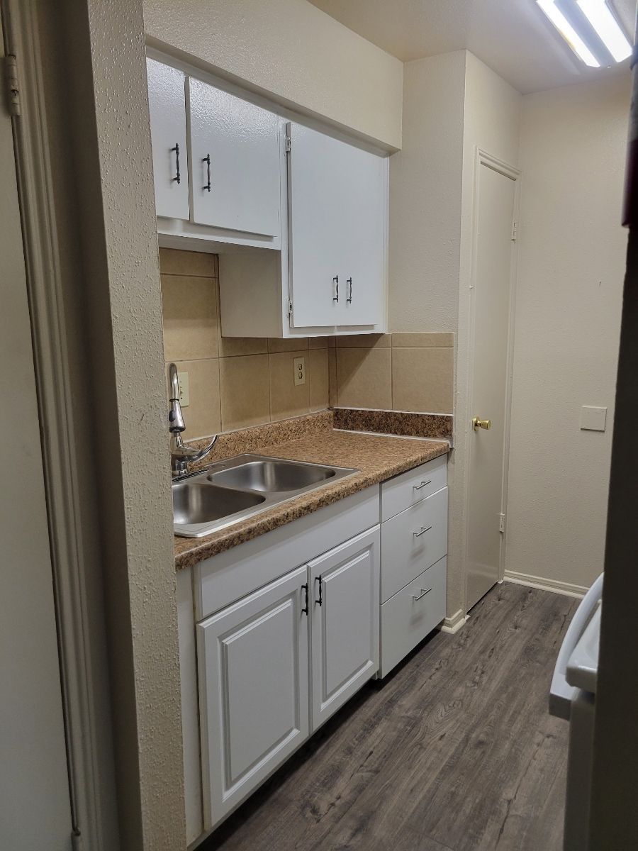A kitchen with white cabinets, and granite countertop