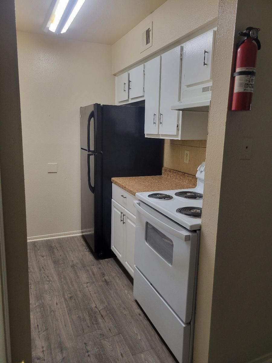 A kitchen with a stove, refrigerator, and fire extinguisher