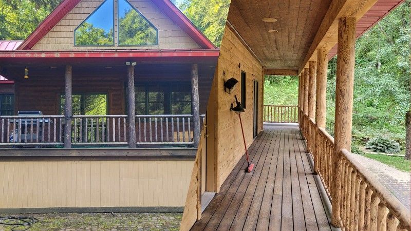A log cabin with a large porch and a long wooden walkway leading to it.